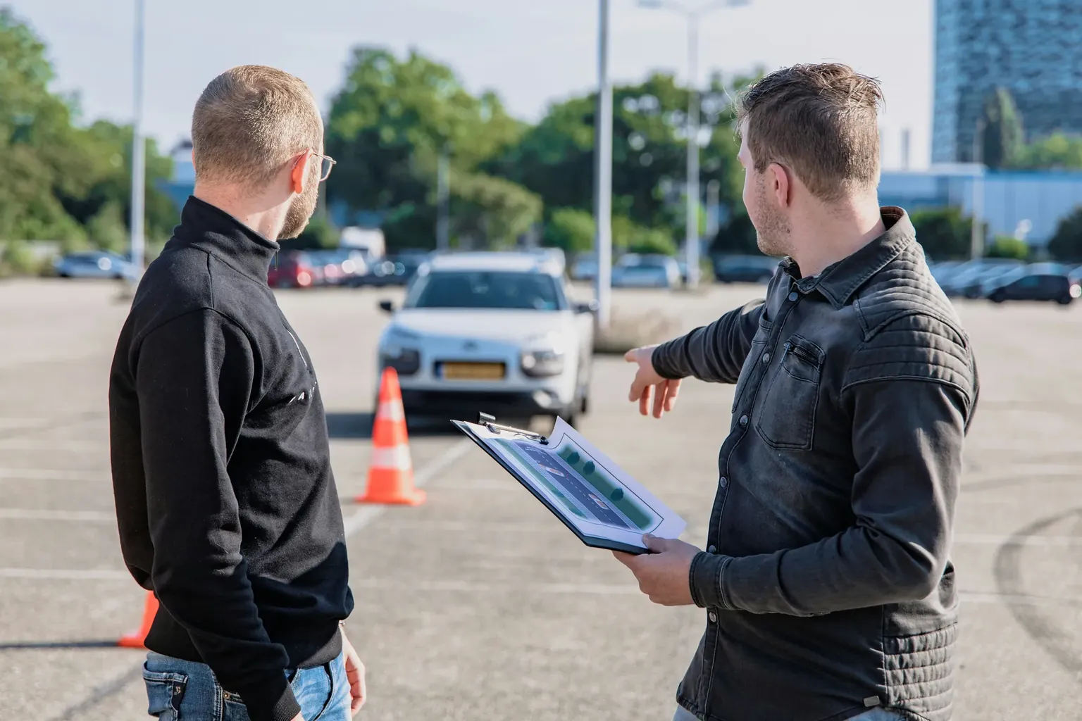 Driving instructor stood outside the car, pointing out a vehicle safety feature