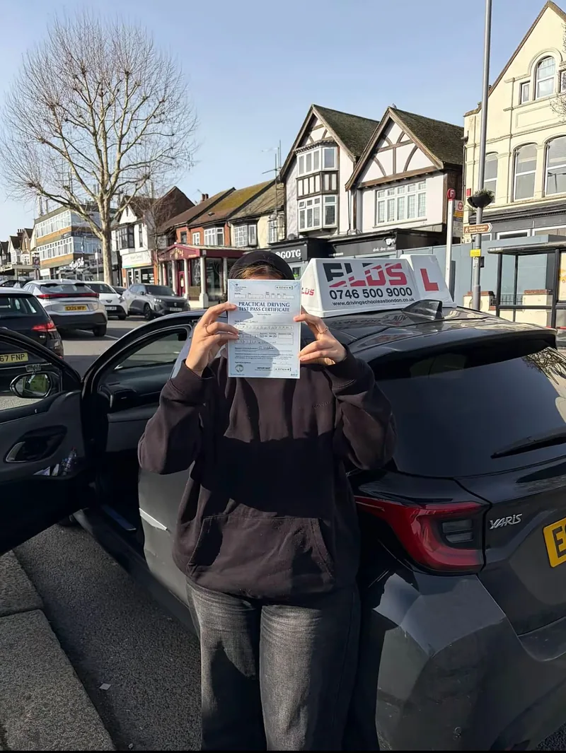 Pupil holding up their pass certificate beside the driving school car